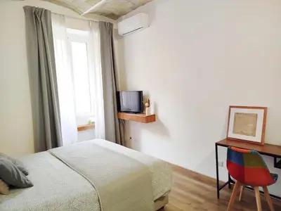 a bedroom with a bed and a desk with a television at Mamomi HOUSE in Rome