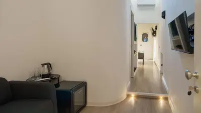 a living room with a couch and a tv and a hallway at Ripetta Boutique Suites in Rome