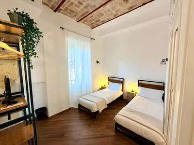 two beds in a room with white walls and wooden floors at Enjoy Vatican Holiday in Rome in Rome