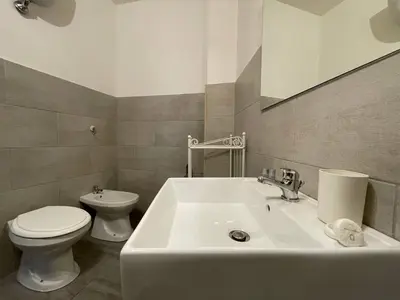 a white bathroom with a toilet and a sink at Spacious and Bright in Rome