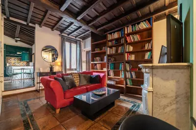 a living room with a red couch and bookshelves at GuestHost - Cozy Trevi Romance in Rome