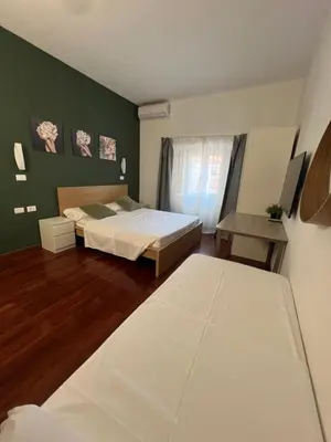 a bedroom with two beds and a green wall at Casa vacanza “Eden” in Rome