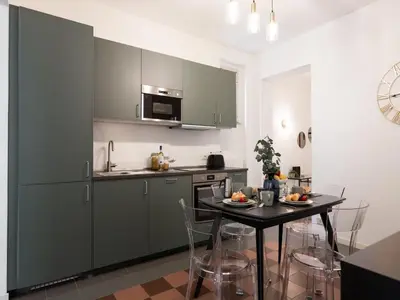 a kitchen with green cabinets and a table with chairs at The Best Rent - Large apartment a few steps from the Trevi Fountain in Rome