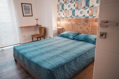 a bedroom with a bed with a blue comforter and a chair at MT apartment in Rome