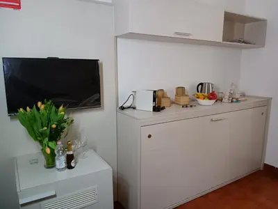 a kitchen with a tv and a white cabinet at ANDENIS TIBER HOUSE in Rome