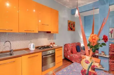a kitchen with orange cabinets and a red couch at Olimpia Apartment in Rome