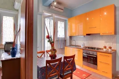 a kitchen with orange cabinets and a table with chairs at Olimpia Apartment in Rome