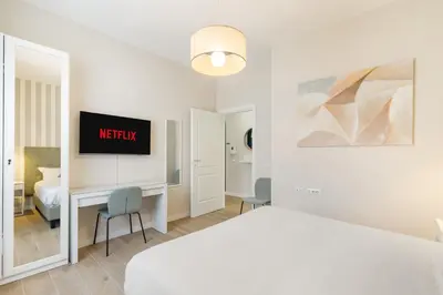 a white bedroom with a bed and a desk with a tv at AlbaDea Apartment in Rome