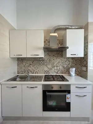 a kitchen with white cabinets and a stove top oven at Claire House in Rome