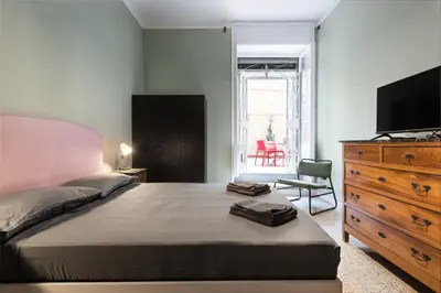 a bedroom with a bed and a dresser and a television at Angelico Vatican Apartment by Oneup Hospitality in Rome