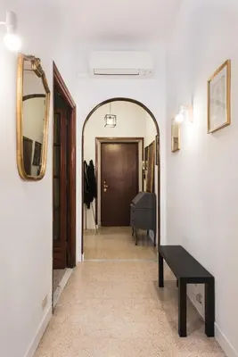 a hallway with a mirror and a table and a door at Angelico Vatican Apartment by Oneup Hospitality in Rome