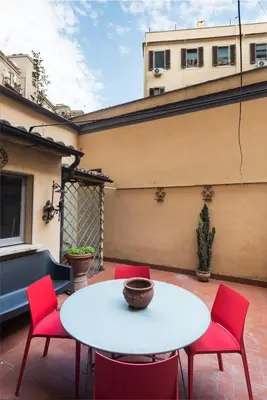 a patio with a white table and red chairs at Angelico Vatican Apartment by Oneup Hospitality in Rome