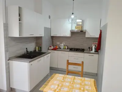 a kitchen with white cabinets and a sink and a chair at Urban cosy rooms in Rome