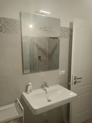 a white bathroom with a sink and a mirror at Urban cosy rooms in Rome