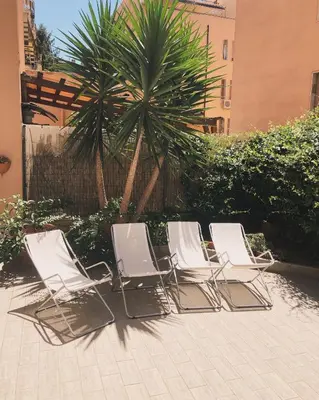 a row of white chairs sitting in front of a palm tree at Maison Balduina in Rome