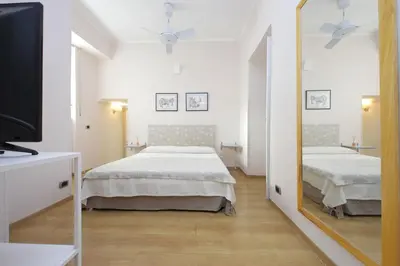 a white bedroom with two beds and a mirror at Vaticano in Rome