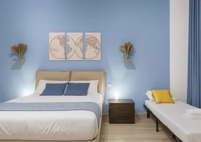 a bedroom with two beds and a blue wall at RomeSweetHome Villa Borghese in Rome