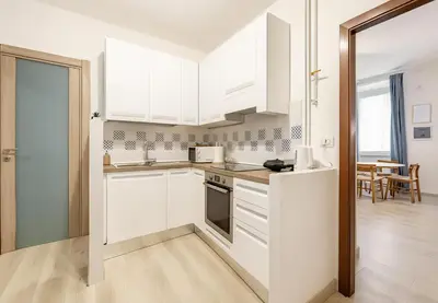 a white kitchen with white cabinets and a dining room at RomeSweetHome Villa Borghese in Rome