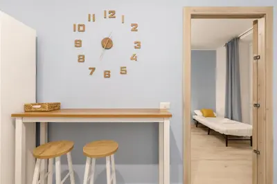 a room with a table and two stools and a clock at RomeSweetHome Villa Borghese in Rome