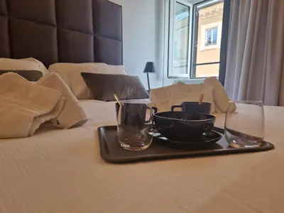 a tray with a bowl and two glasses on a bed at Corso Suite Style in Rome