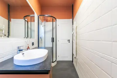 a bathroom with a large white sink and orange walls at LUCIANO LUXURY APARTMENT in Rome