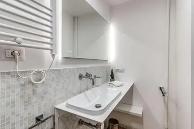 a white bathroom with a sink and a mirror at Vatican Portrait Suites in Rome