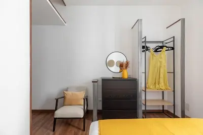 a bedroom with a dresser and a mirror and a chair at iFlat Colosseum Charming Flat in Rome