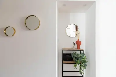 a hallway with three mirrors and a plant on a shelf at iFlat Colosseum Charming Flat in Rome