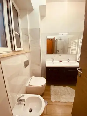 a white bathroom with a toilet and a sink at Large Garden in Rome