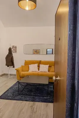 a living room with a yellow couch and a table at Seminterrato al Pıgneto metro C in Rome