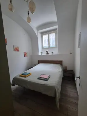 a bedroom with a bed in a white room at Seminterrato al Pıgneto metro C in Rome