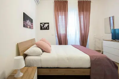 a bedroom with a bed with white sheets and pink pillows at Domus Ascanio by the Vatican in Rome
