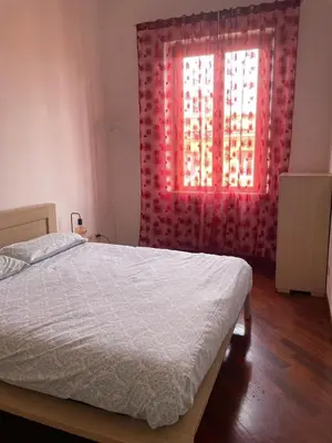 a bedroom with a bed and a window with red curtains at Sun's House in Rome