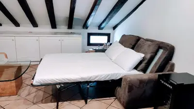 a bed in a room with a chair and a table at Attic Roof Oasi Vaticana in Rome