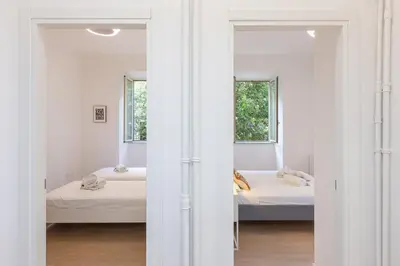 a bedroom with two beds and two windows at Faleria by Rental in Rome in Rome
