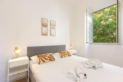 a white bedroom with two beds and a window at Faleria by Rental in Rome in Rome