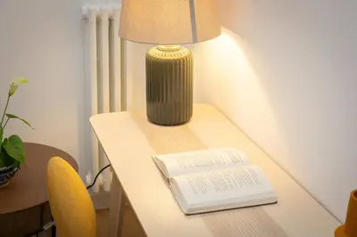 a table with a lamp and a book on it at Faleria by Rental in Rome in Rome