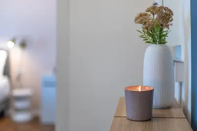 a candle and a vase with flowers on a table at YCH-Bright and cozy flat in Pigneto in Rome