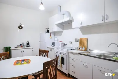 a kitchen with white cabinets and a table and a sink at Pantera Holiday House in Rome