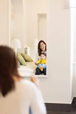 a woman holding a baby in front of a mirror at MC Apartment San Giovanni in Rome