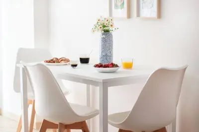 a white table with white chairs and a vase with flowers at Esclusivo Appartamento di design (metro Tiburtina) in Rome