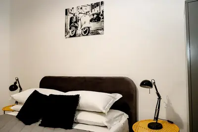 a bed with white pillows and a table with a lamp at MyWay RDR in Rome