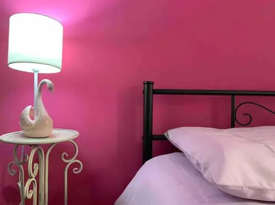 a pink bedroom with a bed and a lamp on a table at Your Happy Home in Rome