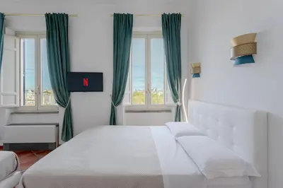 a bedroom with a large white bed with green curtains at The Attico: best view of Rome in Rome