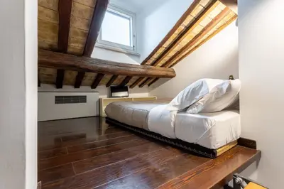 a bedroom with a white bed and wooden floors at The Attico: best view of Rome in Rome
