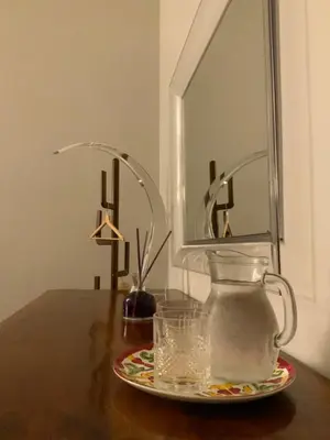 a glass vase on a table with a plate of water at A casa di Pelé suite in Rome
