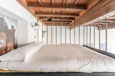 a bedroom with a large white bed with wooden ceilings at Monti Art Loft in Rome