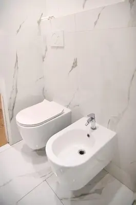 a white bathroom with a toilet and a sink at Via Veneto Luxury Loft in Rome