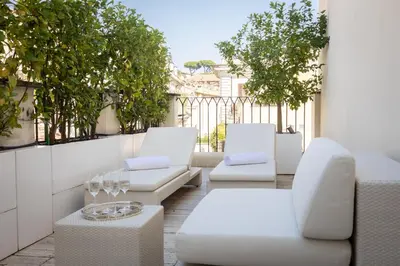 a patio with white chairs and tables on a balcony at Amazing Piazza Venezia with Jacuzzi and terrace in Rome