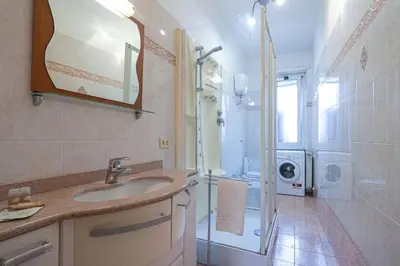 a bathroom with a sink and a shower and a washing machine at Hostme Luminoso Appartamento Metro Marconi in Rome